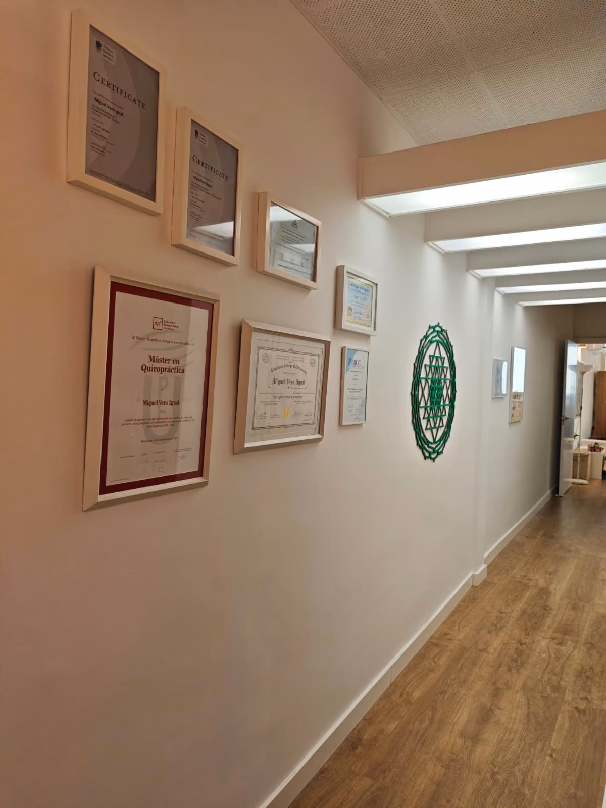 Pasillo de la consulta con los títulos y certificados de Miguel Vera enmarcados en la pared.